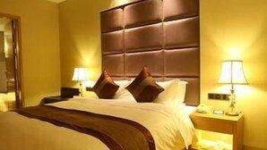 A hotel room with a large bed, two bedside tables with lamps, and a headboard. - Beautiful Landscape Hotel (Liangshan Yi)