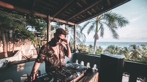 Une cabine de DJ offrant une vue sur l’océan et les palmiers.