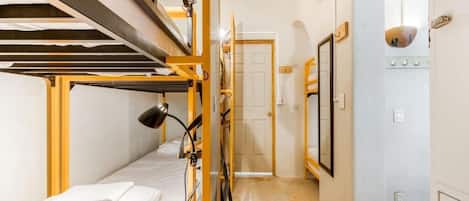 A dormitory room with bunk beds, a desk, and a chair.