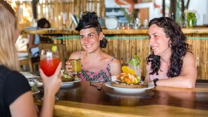 Un groupe de personnes est réuni dans un restaurant dont l’intérieur est en bois et qui est agrémenté d’un décor en bambou.