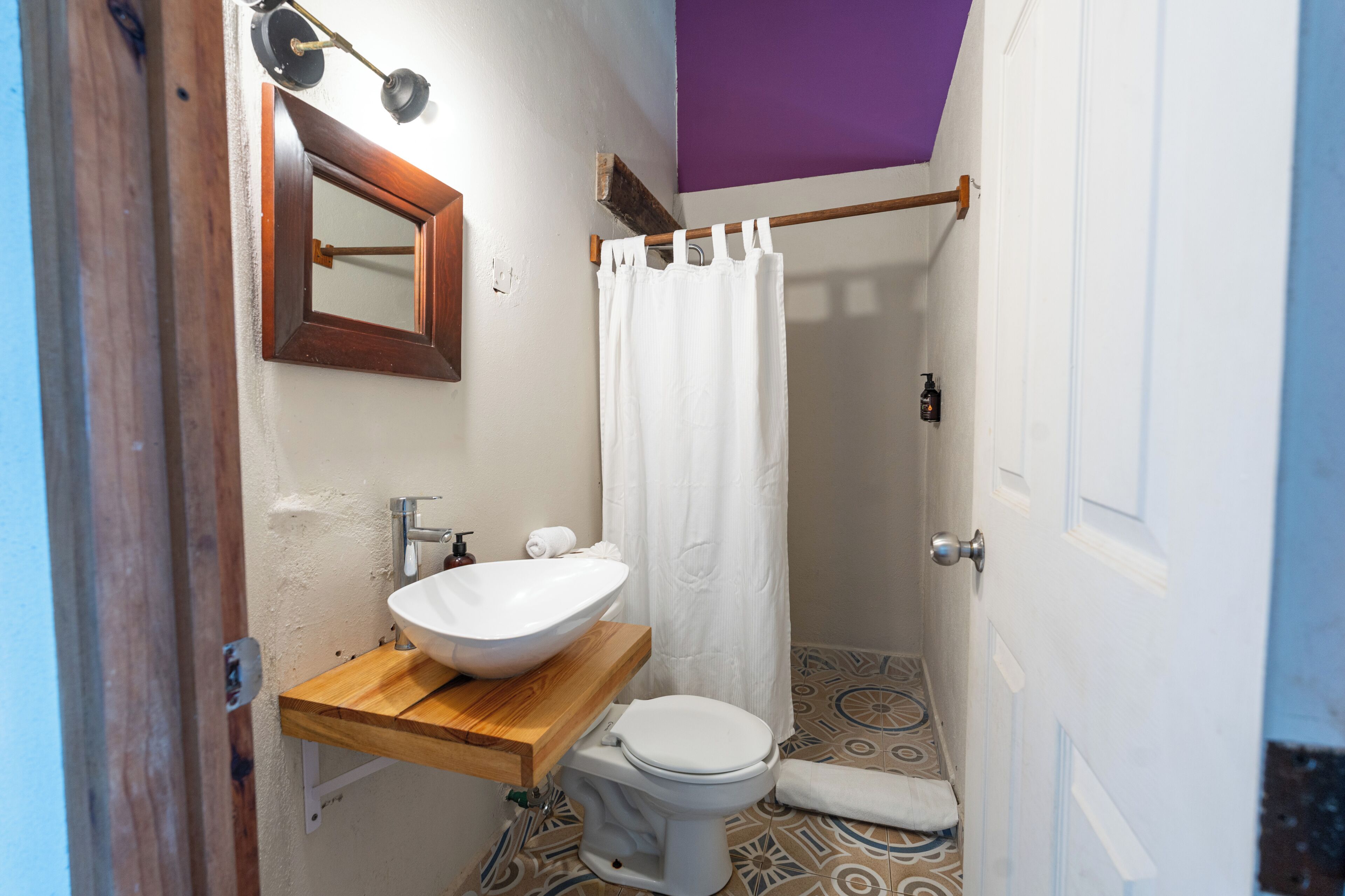 A bathroom with a wooden vanity, white sink, and a shower curtain.