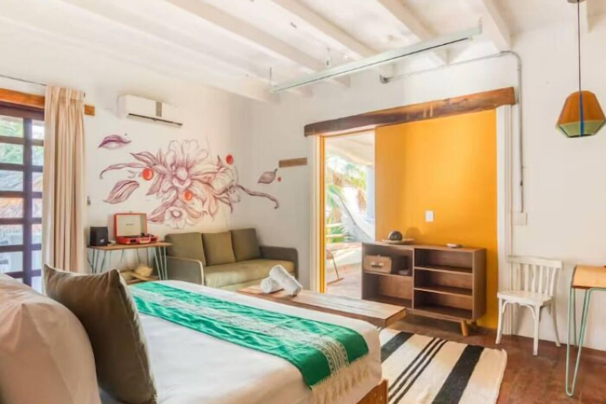 Un dormitorio con cama, escritorio, silla, sofá y puerta corrediza que da a un balcón.