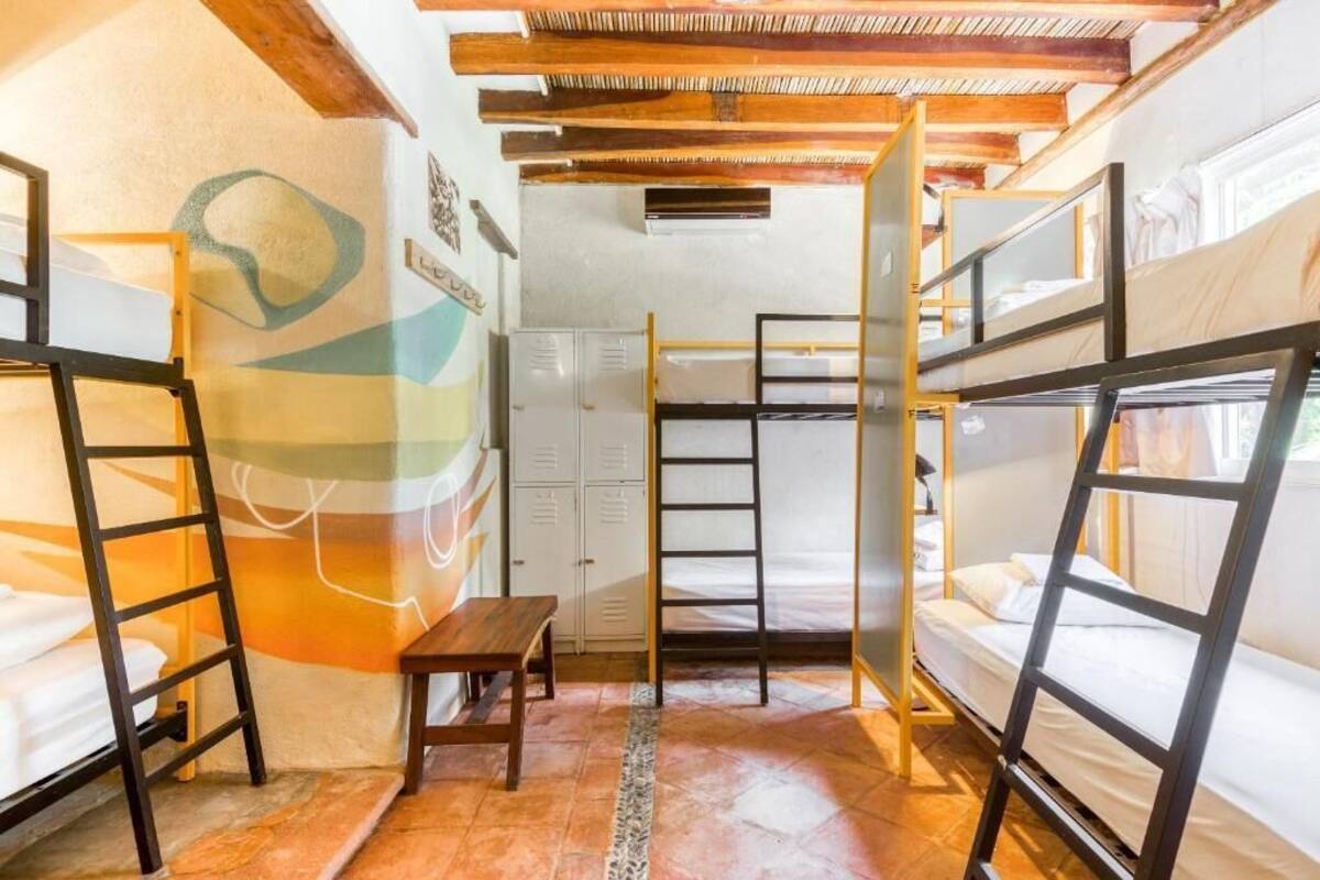 Un dormitorio con literas, una escalera de madera, una mesita y una pared con un diseño geométrico.
