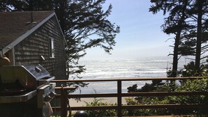 A wooden deck with a grill and a view of the ocean.