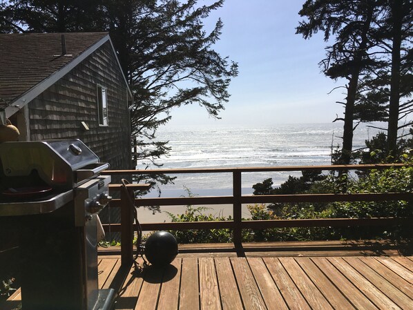 Terraza de madera con una parrilla y vista al océano.