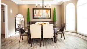 A dining room with a wooden table, four chairs, a chandelier, and a large abstract painting on the wall. - Southern Luxury: Eastchase District 4bd / 3bth (Montgomery)