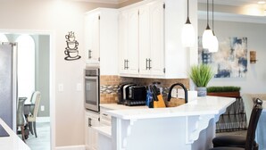 A modern kitchen with white cabinets, a built-in island, and pendant lighting. - Southern Luxury: Eastchase District 4bd / 3bth (Montgomery)