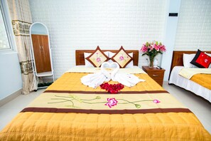Une chambre d’hôtel avec un grand lit, une tête de lit en bois, une table de chevet ornée d’un vase de fleurs et un miroir au mur.