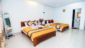 Une chambre d’hôtel avec deux lits, un miroir, une petite table avec un vase, et une salle de bain visible à travers une porte ouverte.