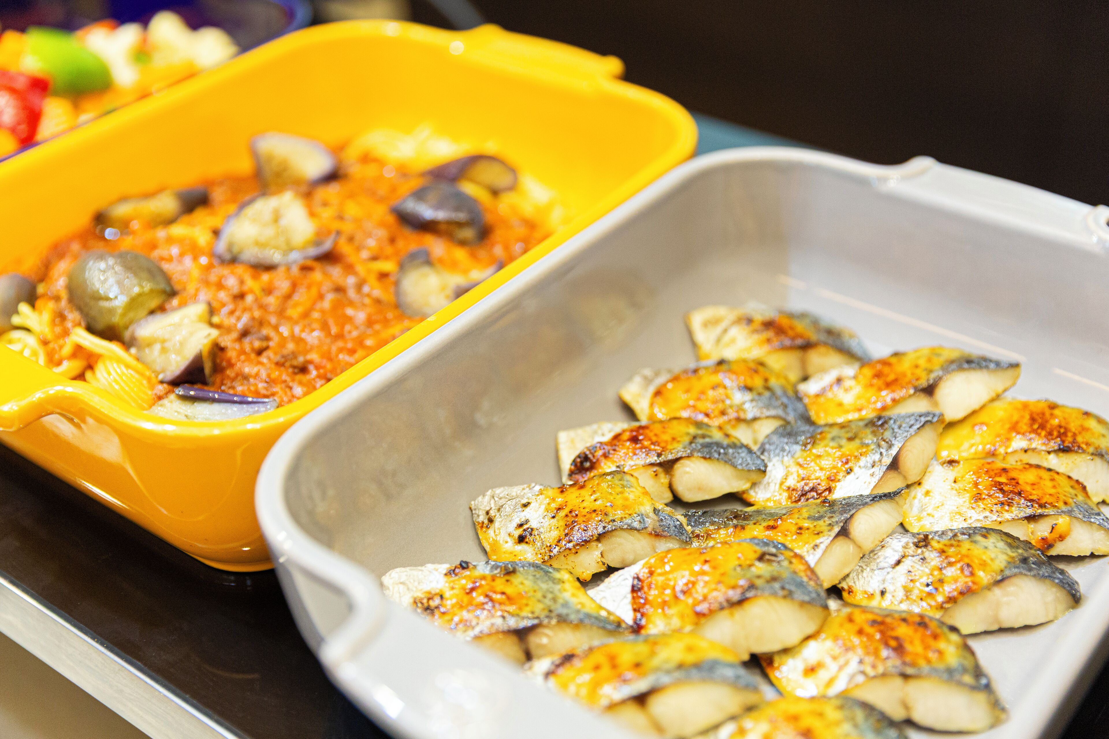 Un vassoio con pesce cotto e un contenitore di salsa.