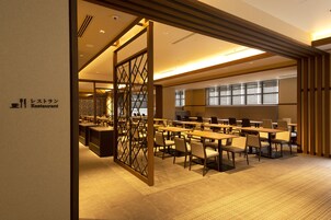Un restaurante con varias mesas y sillas, un separador de madera, y un letrero que indica que es un restaurante.
