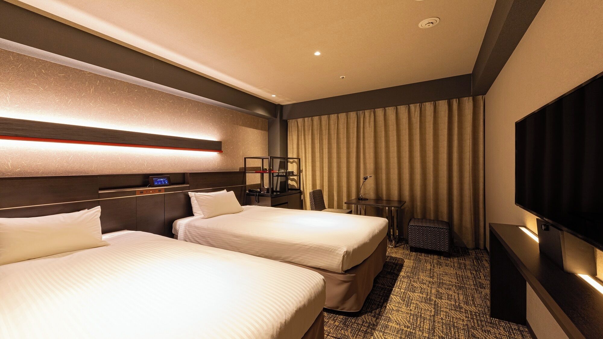 Une chambre d’hôtel avec deux lits, un bureau, une télévision et un minibar.