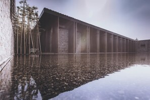 A modern building with a reflective pool, bamboo trees, and a brick wall. - Tsingpu Yangzhou Retreat (Yangzhou)