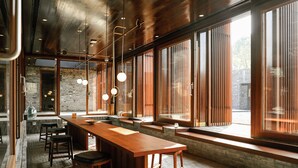 Una cocina moderna con una encimera de madera larga, taburetes de bar y grandes ventanales que dejan entrar luz natural.