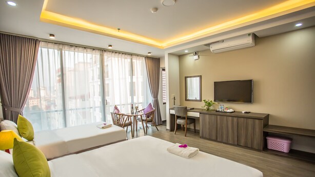 Una habitación de hotel con una cama grande, un escritorio con computadora, un televisor y una ventana con cortinas.