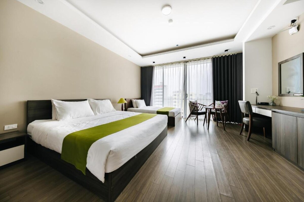 A hotel room with a large bed, a desk, and a chair.