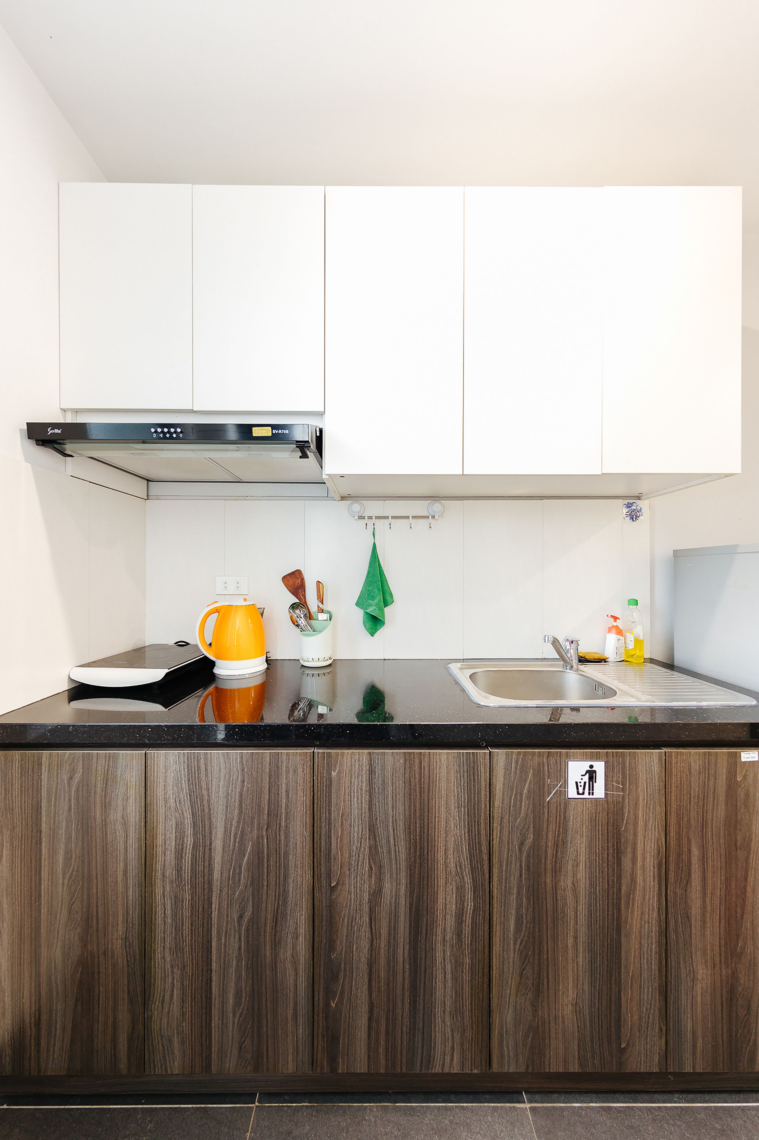 A modern kitchen with white cabinets, a black countertop, and a stainless steel sink.