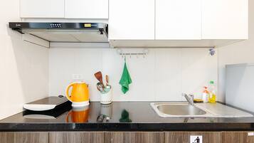 A modern kitchen with white cabinets, a black countertop, and a stainless steel sink.