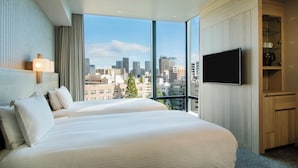 A hotel room with a large bed, a TV, and a view of the city skyline. - Hotel Keihan Tsukiji Ginza Grande (Tokyo)
