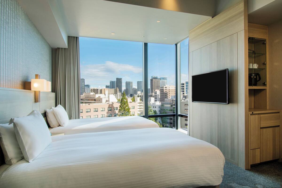 A hotel room with a large bed, a TV, and a view of the city skyline.
