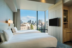 A hotel room with a large bed, a TV, and a view of the city skyline. - Hotel Keihan Tsukiji Ginza Grande (Tokyo)