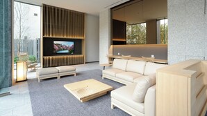 Una sala de estar moderna con un televisor de pantalla plana grande, un sofá, una mesa de centro y un comedor.