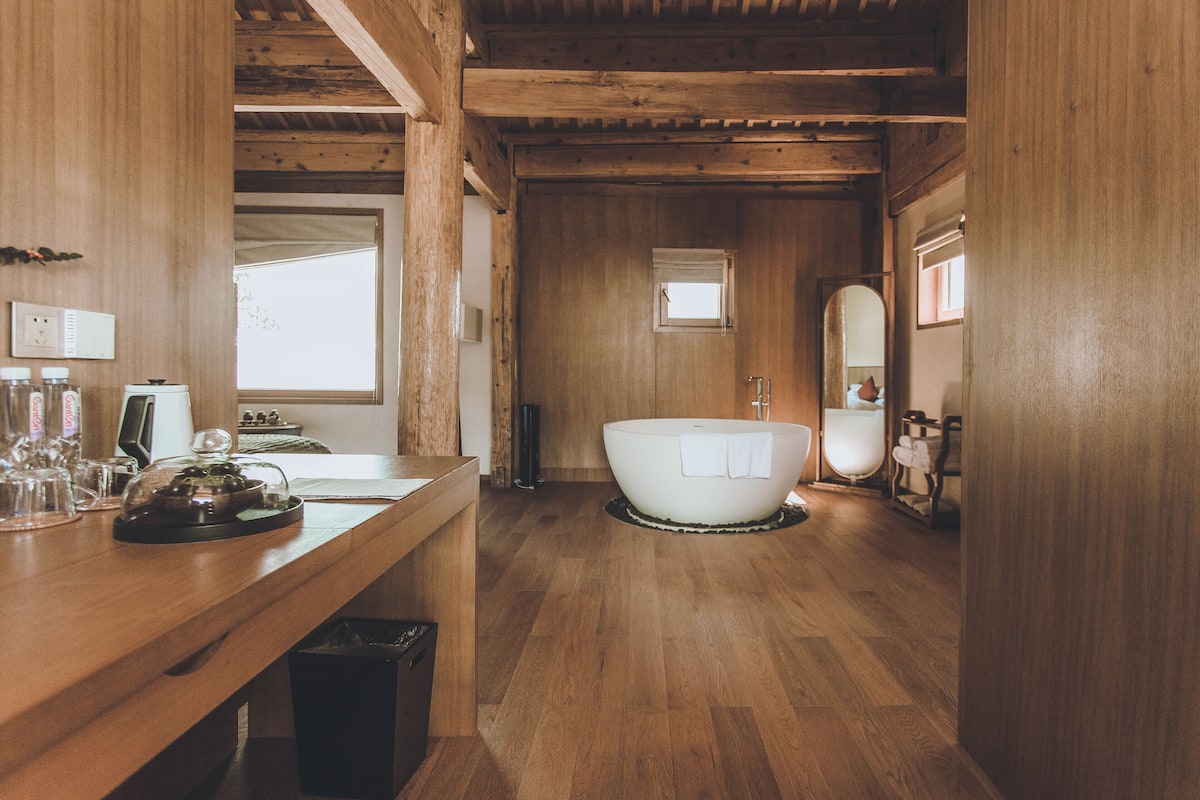 A wooden interior with a bathtub, a sink, and a mirror.