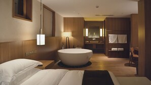 A modern hotel room with a large bathtub, a bed, a wooden vanity, and a mirror. - Tsingpu Lijiang Baisha Retreat (Lijiang)