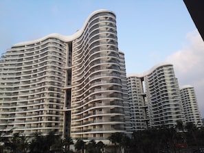 A modern high-rise building with a curved facade, multiple balconies, and a central atrium.
