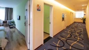 Un pasillo de hotel con piso alfombrado, un comedor con mesa y sillas, y un cartel que indica disponibilidad de WiFi.