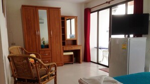 A hotel room with a bed, a wooden wardrobe, a desk, a chair, a television, and a refrigerator. - A&B Hotel (Hua Hin)