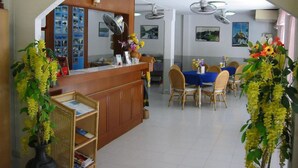 A reception area with a counter, seating, and decorative plants. - A&B Hotel (Hua Hin)