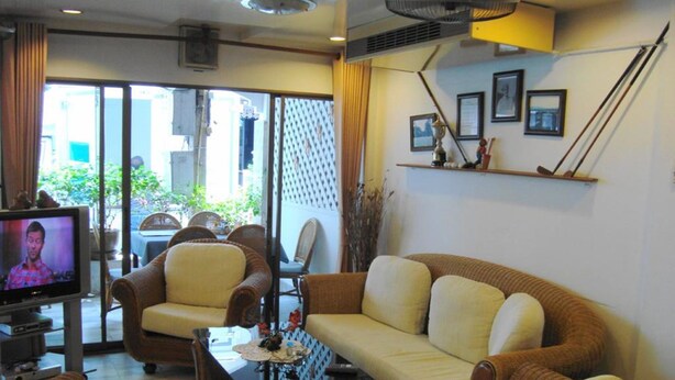 A living room with a sofa, chairs, a television, and a fan. - A&B Hotel (Hua Hin)