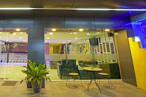 A hotel lobby with a seating area, a reception desk, and a large potted plant. - Holidays Home (Pattaya)