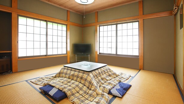 A tatami mat room with a tatami bed, a small table, and a television. - Petit House Hiromi (Minamiuonuma)