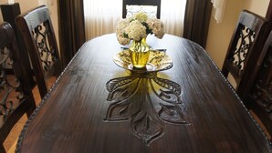 Una mesa de comedor de madera con un jarrón de flores de cristal, rodeada de sillas ornamentales.
