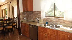 Una cocina con encimeras de granito, fregaderos de acero inoxidable, armarios de madera y lavavajillas.
