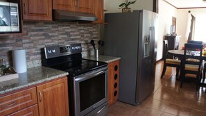 Eine Küche mit Holzschränken, einem Edelstahlherd, einem Kühlschrank und einem Essbereich mit Tisch und Stühlen.