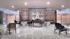A modern lobby with a central seating area, a reception desk, and a decorative wall with vertical elements. - Atour Hotel Xinzhuang Shanghai (Shanghai)