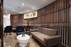 A modern interior with a sofa, chairs, a coffee table, and a decorative plant. - Atour Hotel Xinzhuang Shanghai (Shanghai)