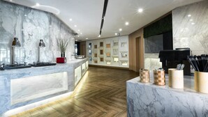 A modern hotel lobby with marble countertops, a wooden floor, and a reception desk with a black speaker. - Atour Hotel Xinzhuang Shanghai (Shanghai)