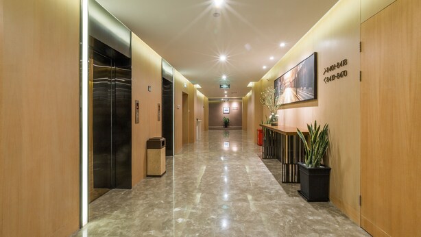 A modern hotel corridor with elevators, a reception desk, and potted plants. - Atour Hotel Xinzhuang Shanghai (Shanghai)