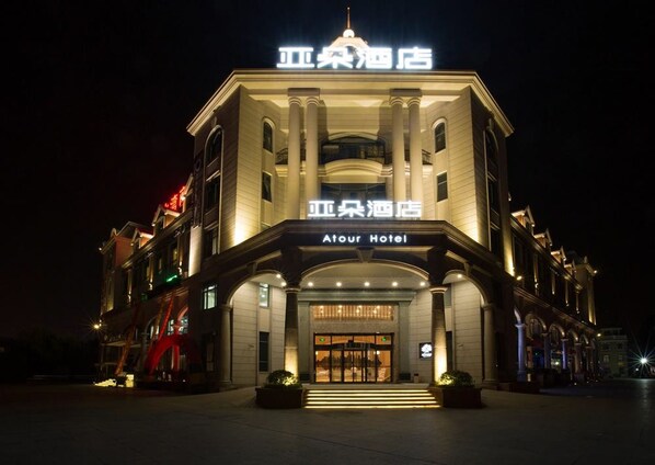 A hotel with a classic architectural style, featuring a prominent entrance with steps leading up to the door, and illuminated signage above the entrance. - Atour Hotel Xinzhuang Shanghai (Shanghai)