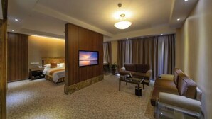 A hotel room with a bed, a TV, a sofa, and a desk. - Peony Hotel (Luoyang)