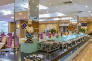 Zona de bufé con diversas opciones de comida y una estatua de chef.