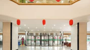 A spacious lobby with a modern design, featuring a central revolving door and a glass railing overlooking the entrance.