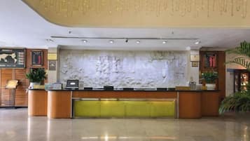 A reception desk with a marble wall, a plant, and a framed map on the wall.
