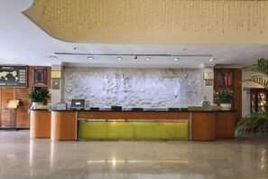 Una recepción con una pared de mármol, una planta y un mapa enmarcado.