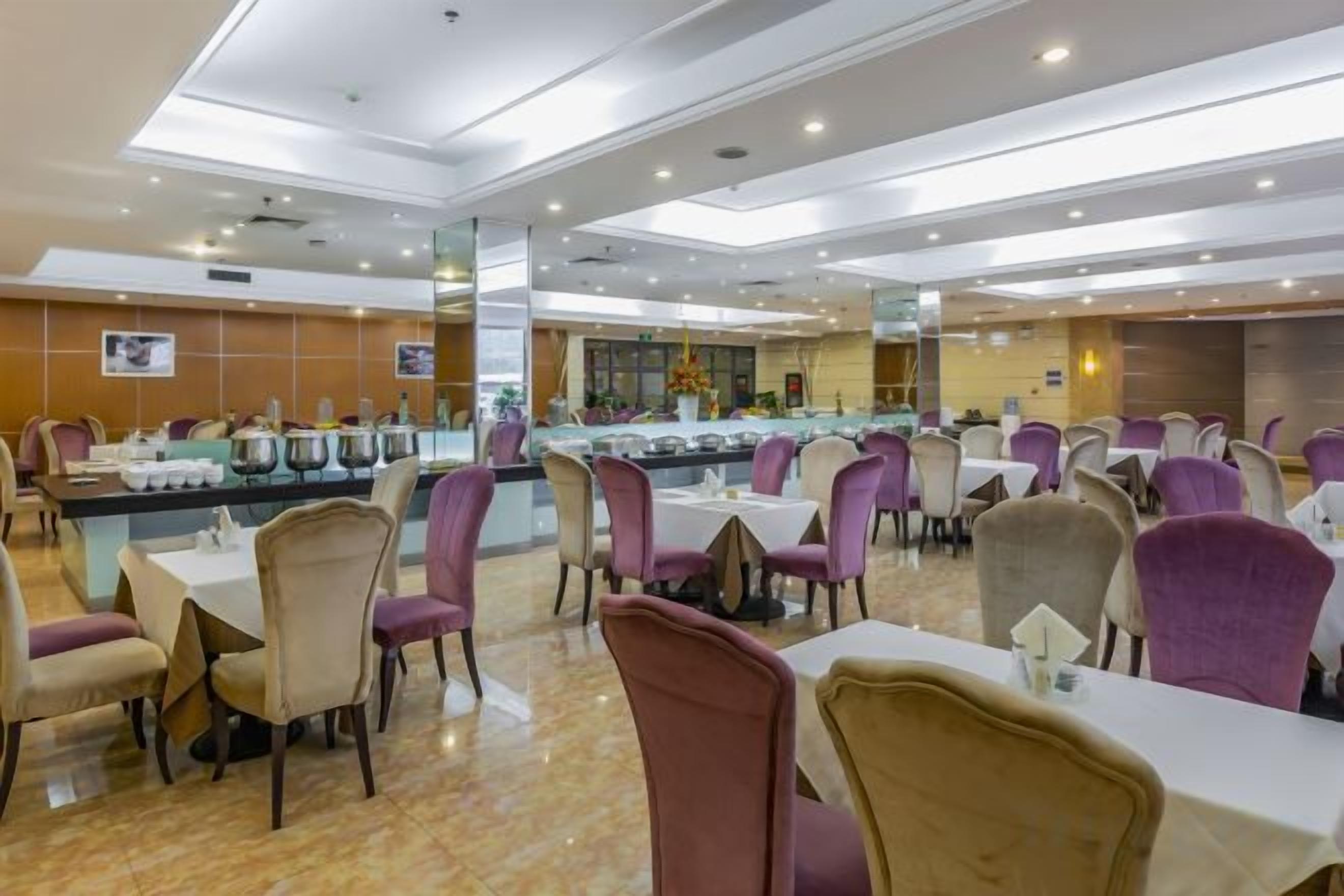 A dining area with multiple tables and chairs, a buffet line, and a counter with food items.