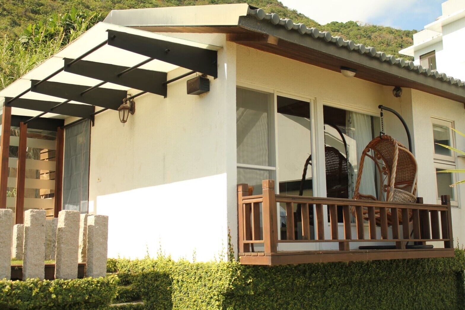 A building with a covered porch, large windows, and a hanging chair.